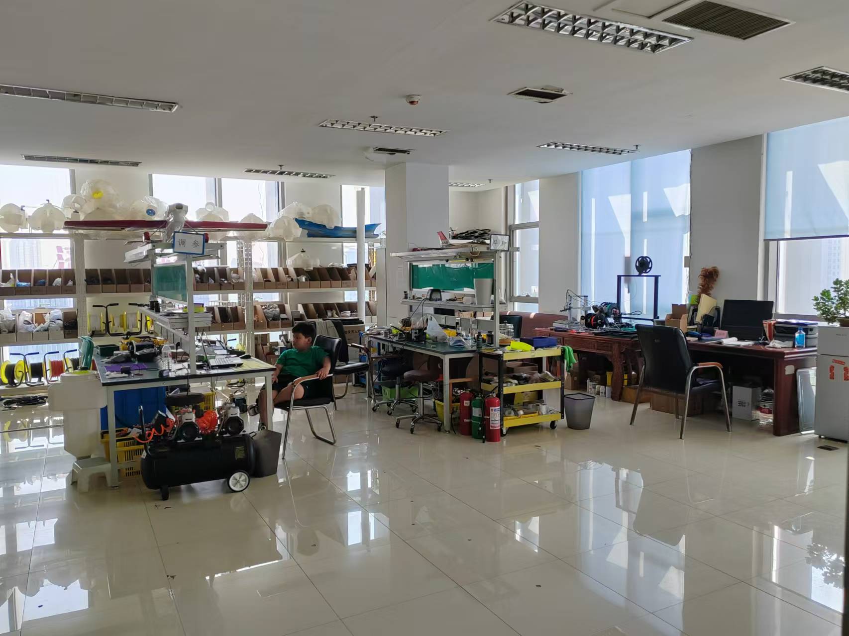 About 100Drone – Your Trusted Source for Drone Parts, Accessories, and DIY Resources 6 Organized R&D workshop with drone components, shelving, and assembly benches