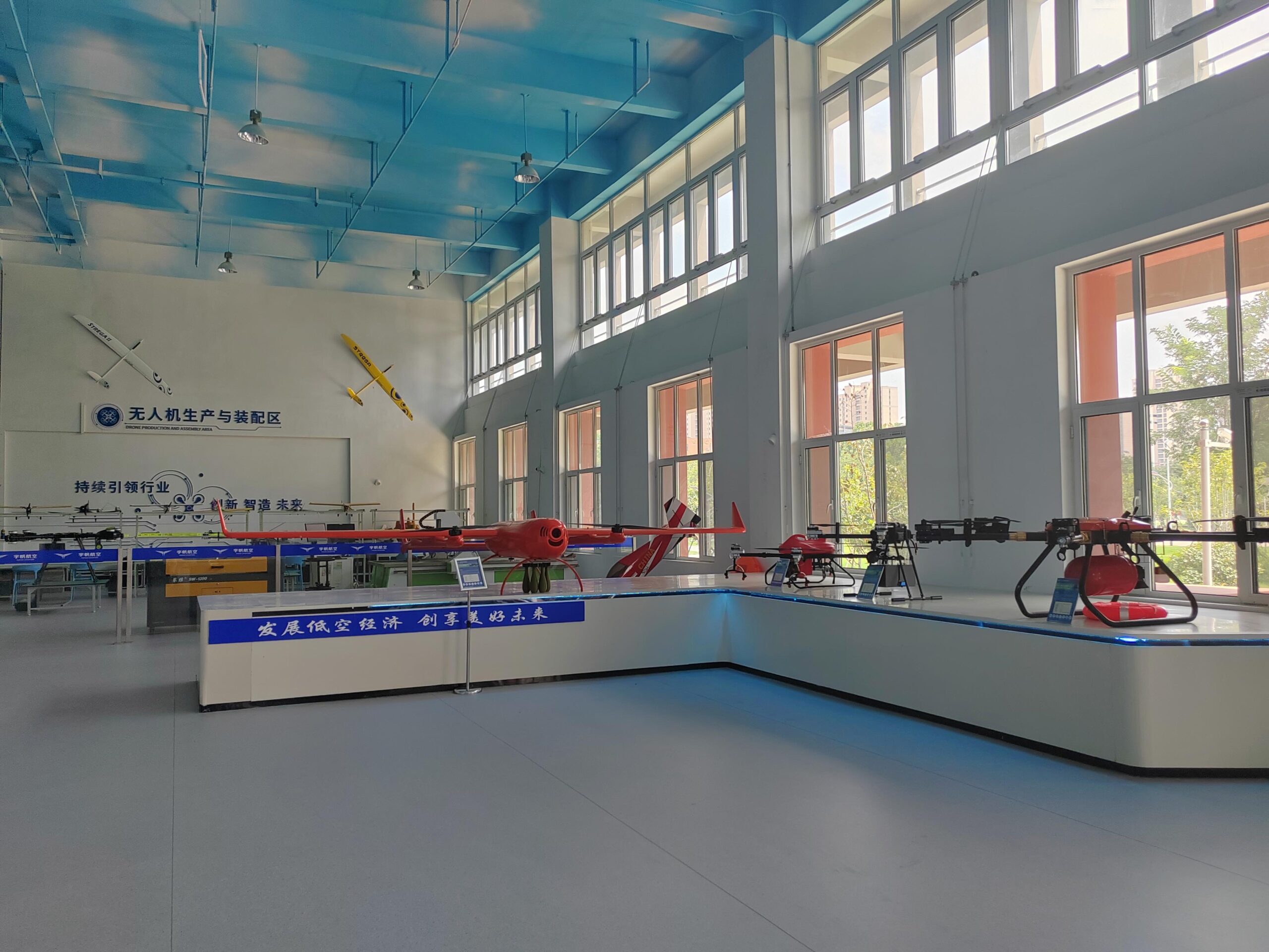 About 100Drone – Your Trusted Source for Drone Parts, Accessories, and DIY Resources 11 Industrial UAV display platform with large red fixed-wing drone and multi-rotor models