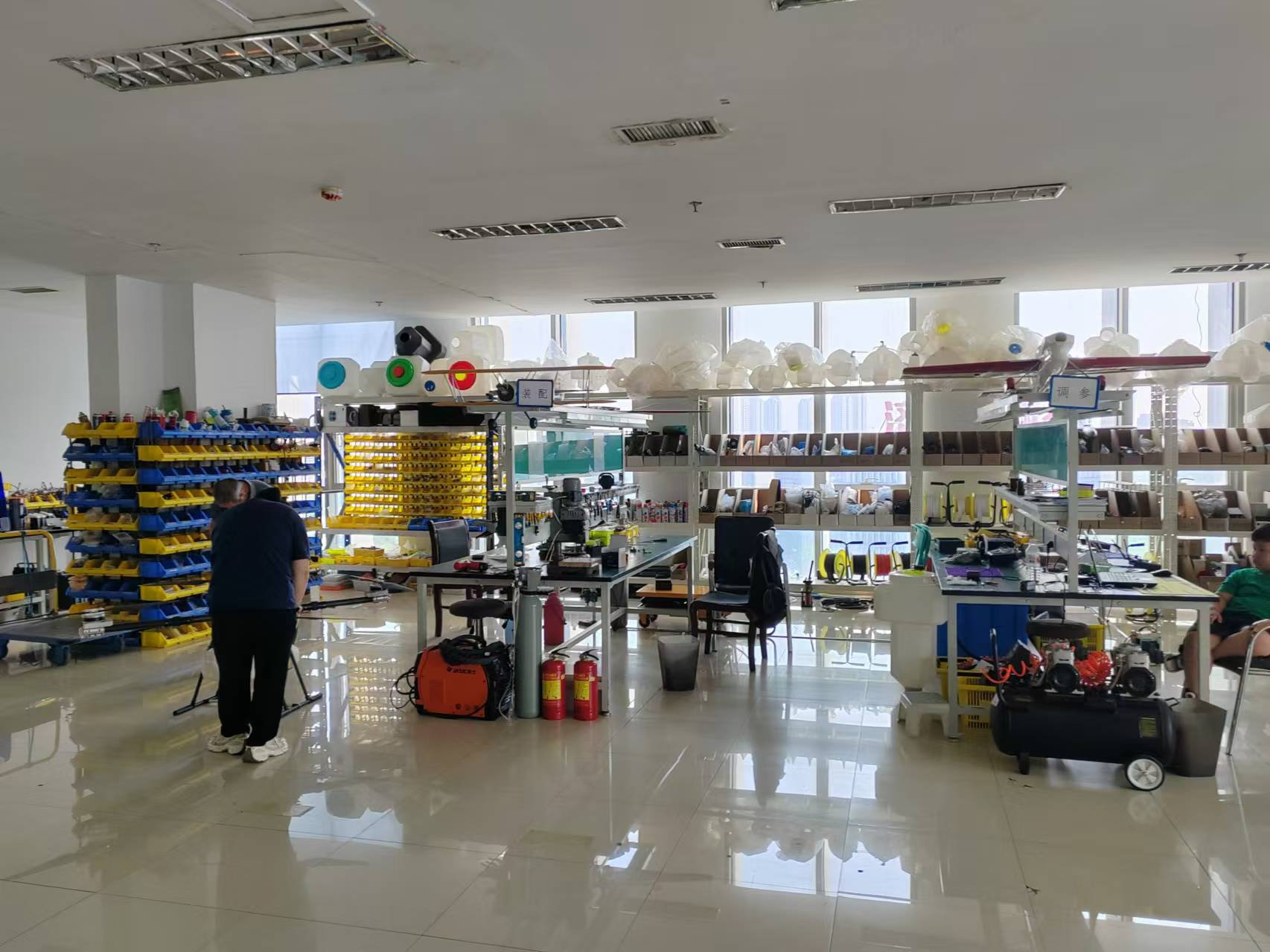 About 100Drone – Your Trusted Source for Drone Parts, Accessories, and DIY Resources 14 Active drone assembly floor with technicians working on UAV frames and component inventory